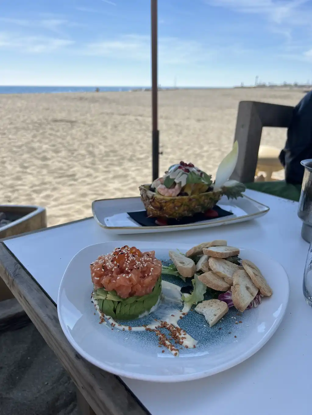 Selección de platos en mesa de madera con vista al mar en Camuri Las Cuchis