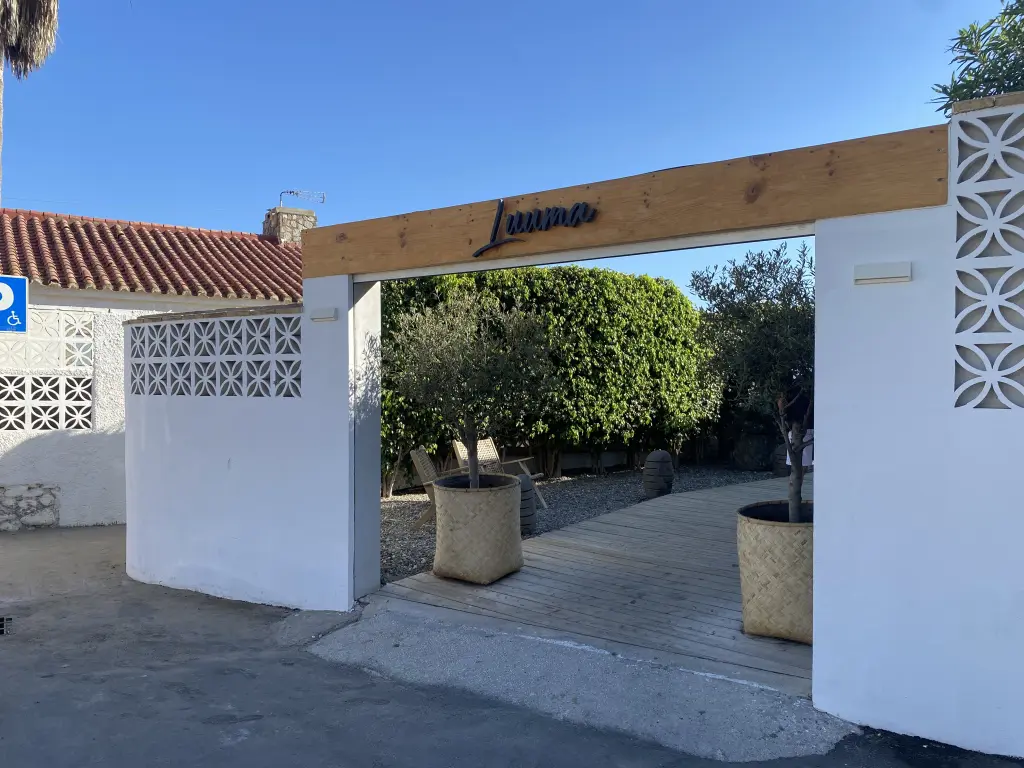 Entrada de Luuma Beach con madera natural y plantas