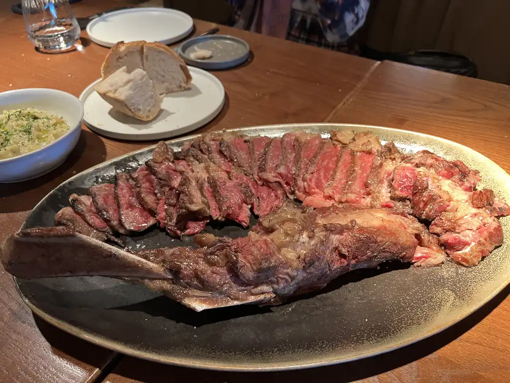 Roostiq Marbella perfectly grilled T-bone steak showcasing expert wood-fired cooking technique