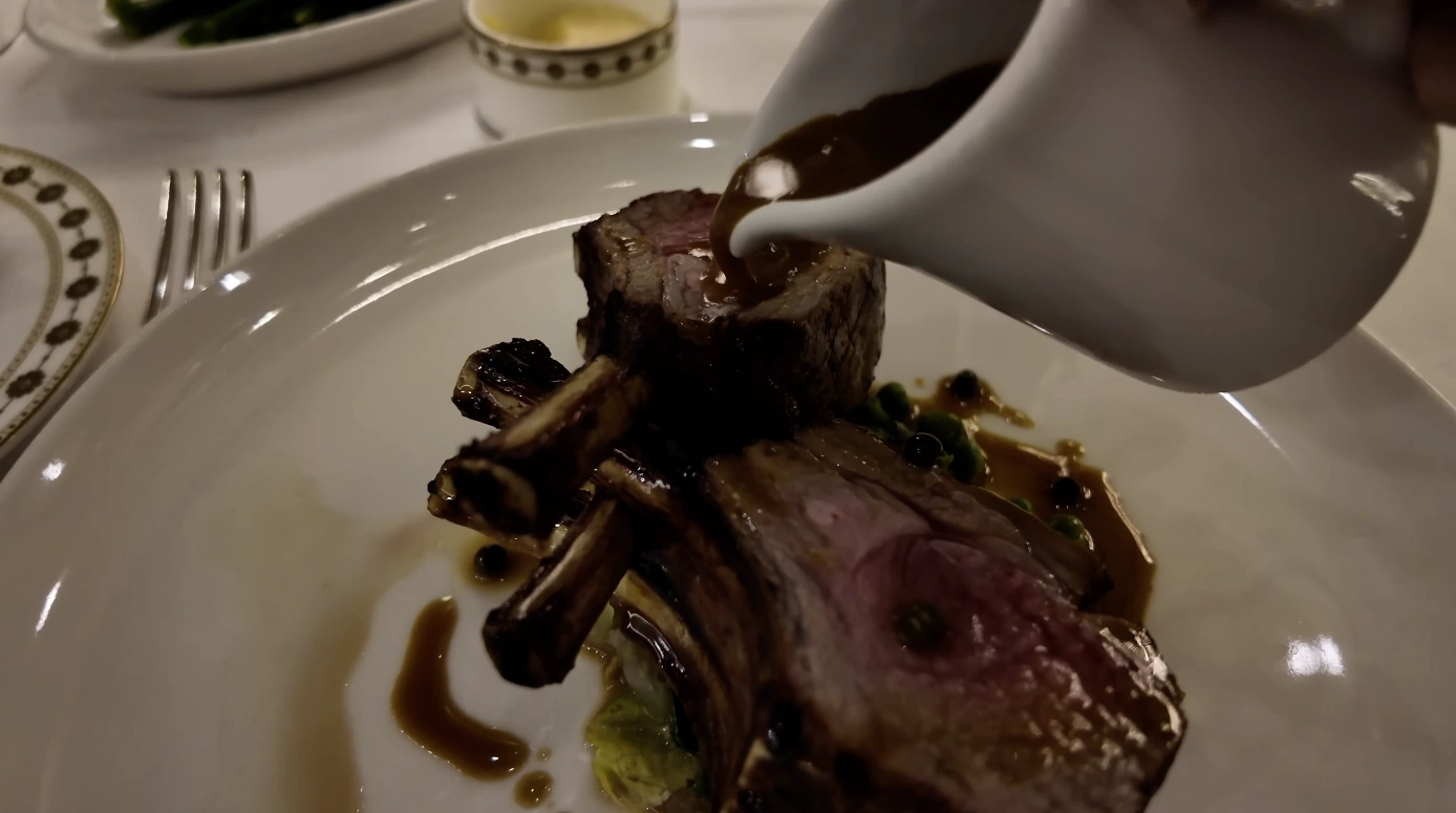 The Langham London fine dining — rack of lamb with jus being poured