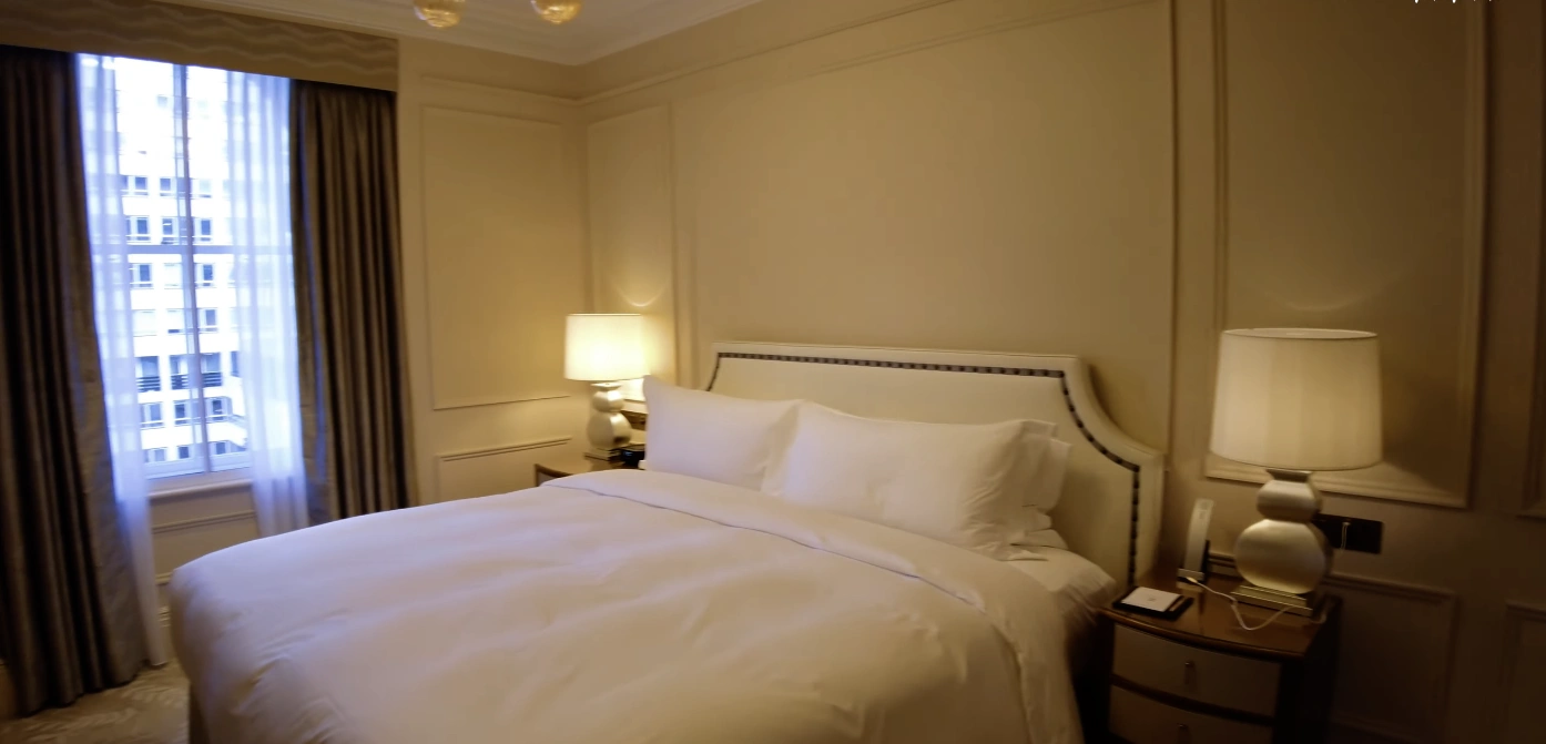 The Langham London — King bedroom with white bedding and city views