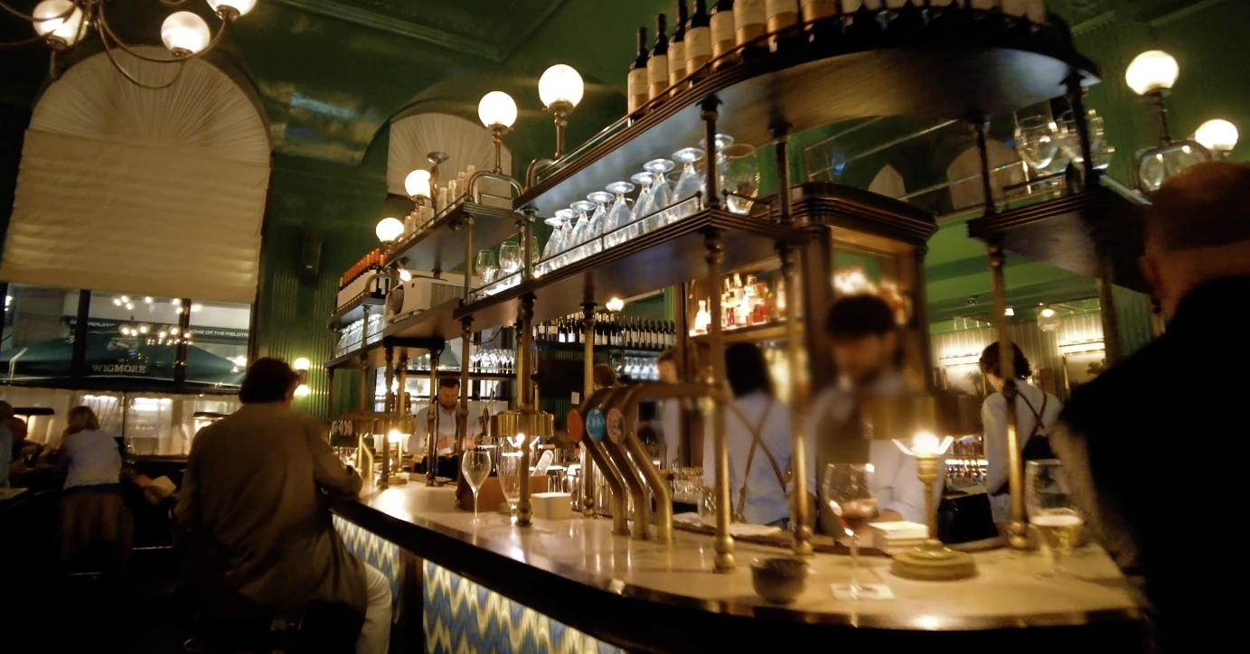 The Wigmore at The Langham London — deep green interior with brass counter at evening