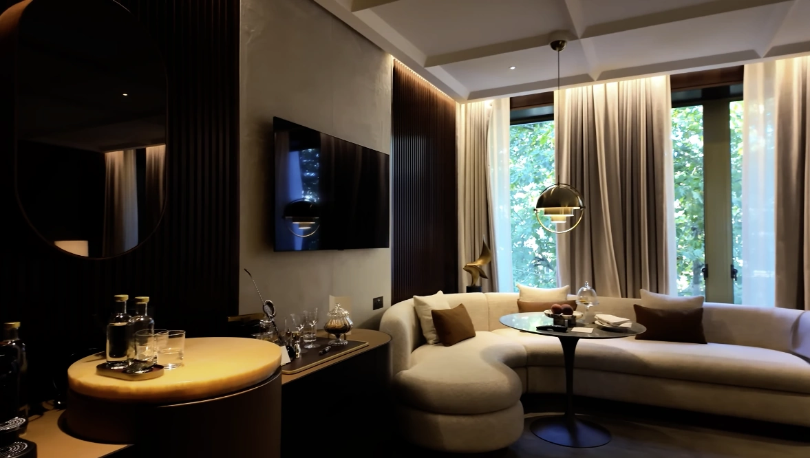 The Chancery Rosewood — Junior Suite living room with curved sofa, minibar and garden views